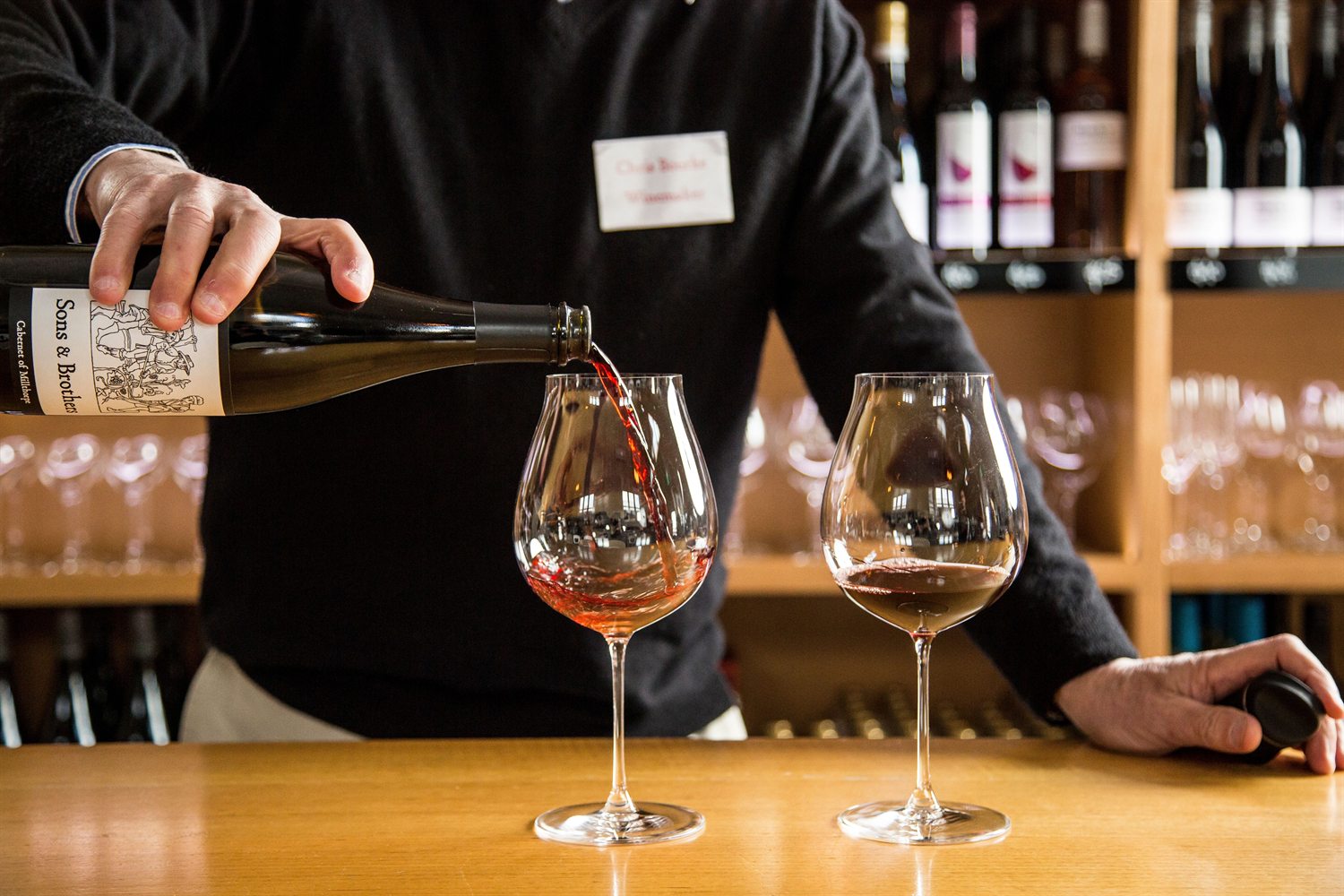 A winemaker pouring a tasting of local red wine at a cellar door in the Orange region, NSW