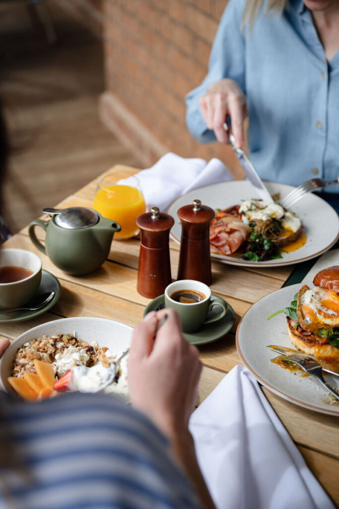 Breakfast with granola, eggs, toast, coffee, and orange juice on a wooden table