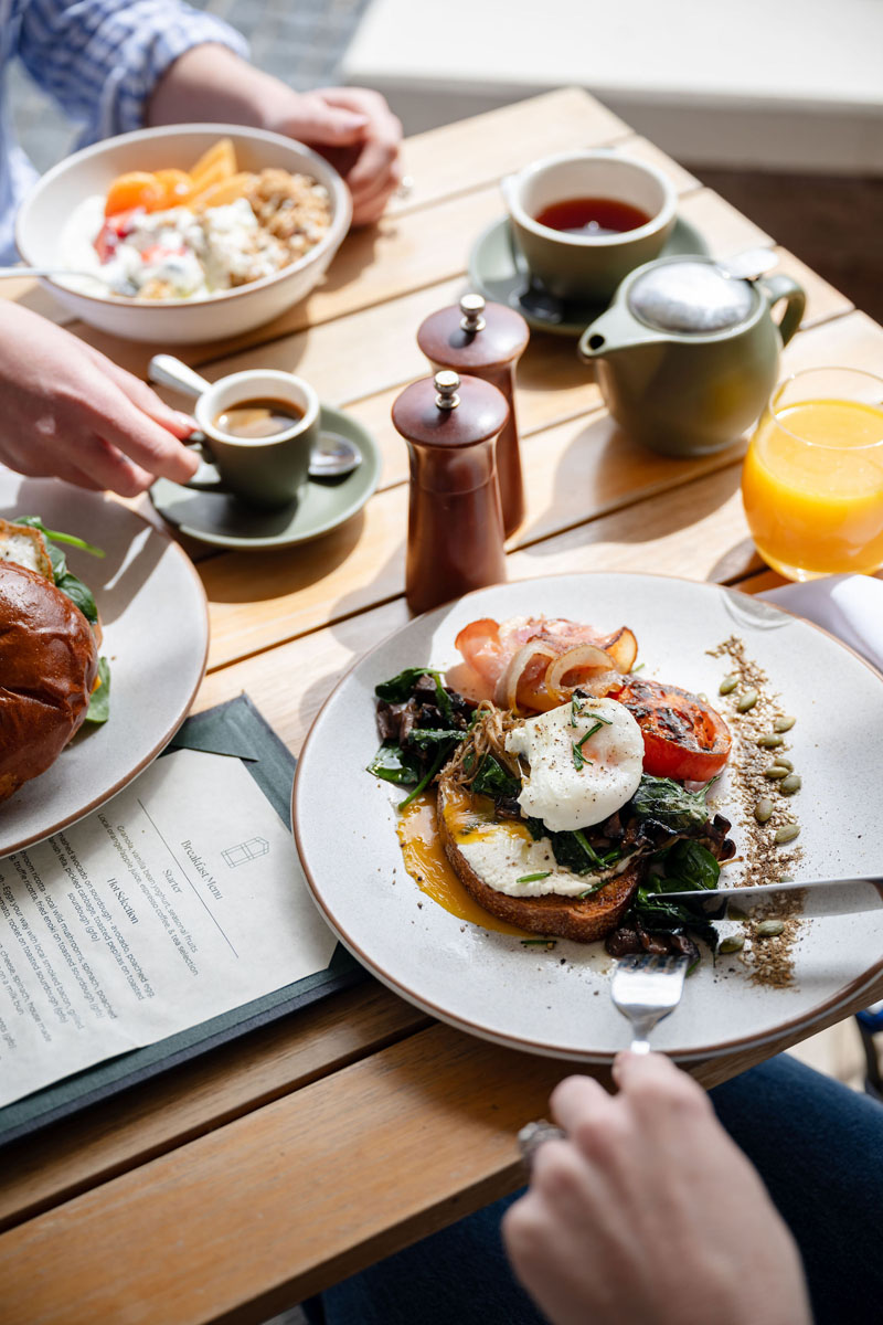 Breakfast meal with poached eggs, toast, vegetables, coffee and juice on wooden table